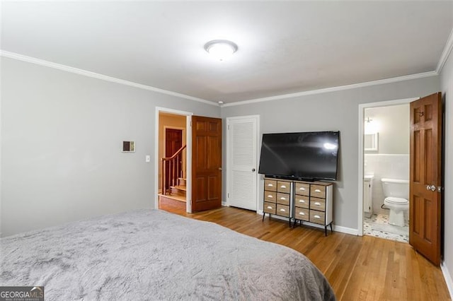 bedroom featuring hardwood / wood-style flooring, crown molding, and ensuite bath