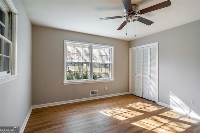 unfurnished bedroom with ceiling fan, a closet, and light wood-type flooring