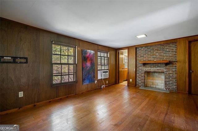 unfurnished living room featuring a fireplace, hardwood / wood-style floors, cooling unit, and wooden walls