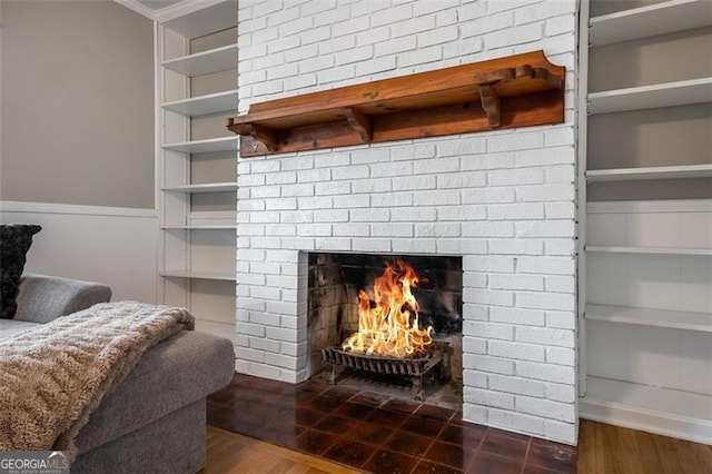 room details with crown molding, hardwood / wood-style floors, built in features, and a brick fireplace