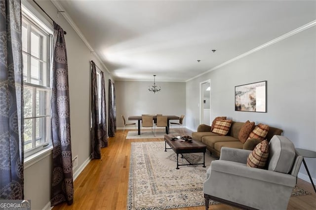 living room featuring a chandelier, light wood-type flooring, and crown molding