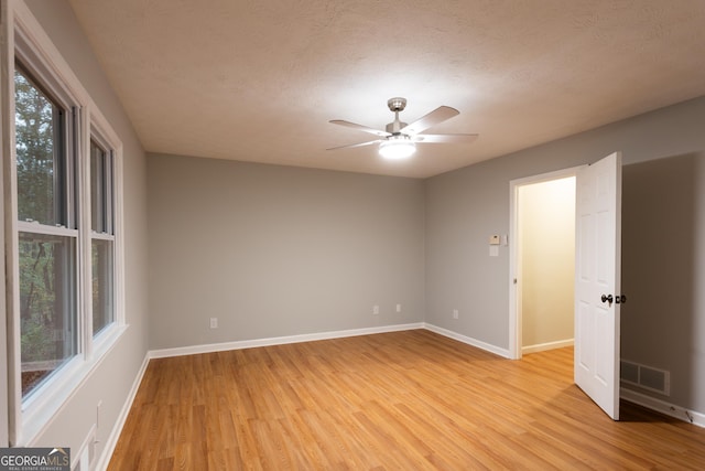 unfurnished room with light wood-type flooring, ceiling fan, and a textured ceiling