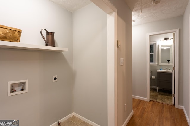 laundry area with washer hookup, a textured ceiling, light hardwood / wood-style floors, and electric dryer hookup