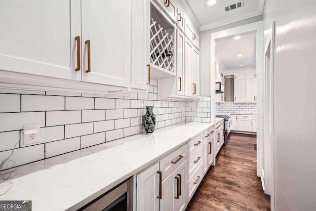 kitchen featuring dark hardwood / wood-style floors, white cabinetry, light stone countertops, and ornamental molding