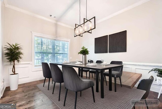 dining area featuring wood-type flooring, ornamental molding, and an inviting chandelier