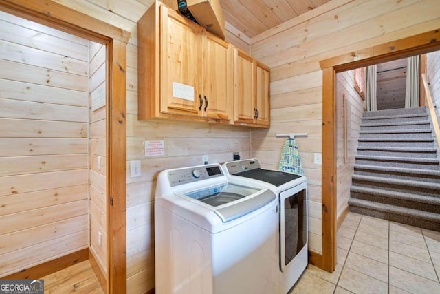 clothes washing area featuring cabinets, wood ceiling, wooden walls, light tile patterned floors, and independent washer and dryer