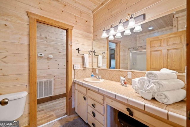 bathroom featuring wooden ceiling, tile patterned flooring, wood walls, vanity, and a shower with shower door