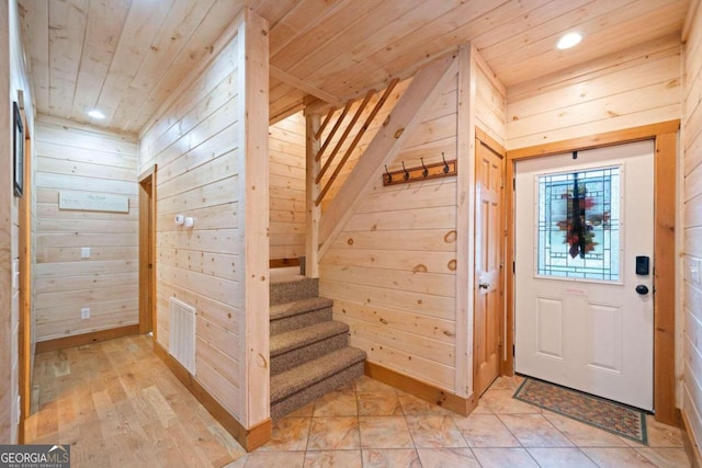 entrance foyer featuring light hardwood / wood-style floors, wooden ceiling, and wooden walls