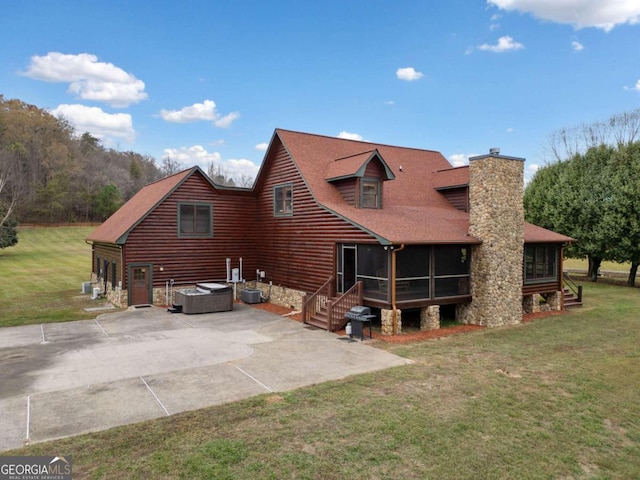 rear view of property featuring a sunroom, a patio area, a yard, and a hot tub