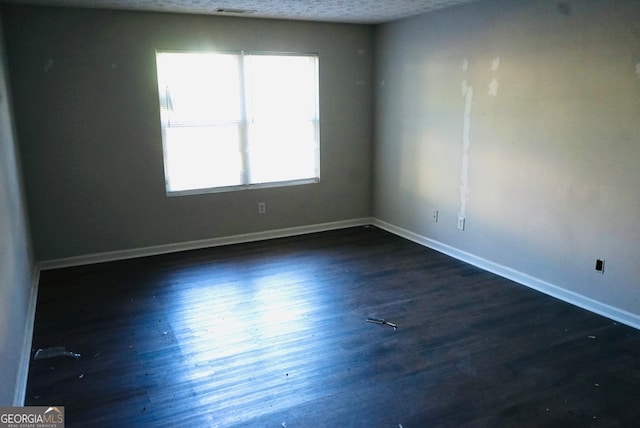 unfurnished room featuring a textured ceiling and dark hardwood / wood-style flooring