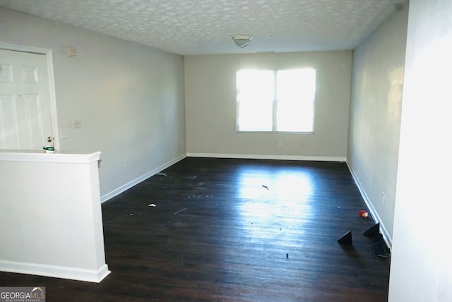 spare room featuring dark hardwood / wood-style flooring and a textured ceiling