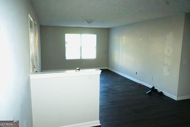 empty room with a textured ceiling and dark hardwood / wood-style flooring