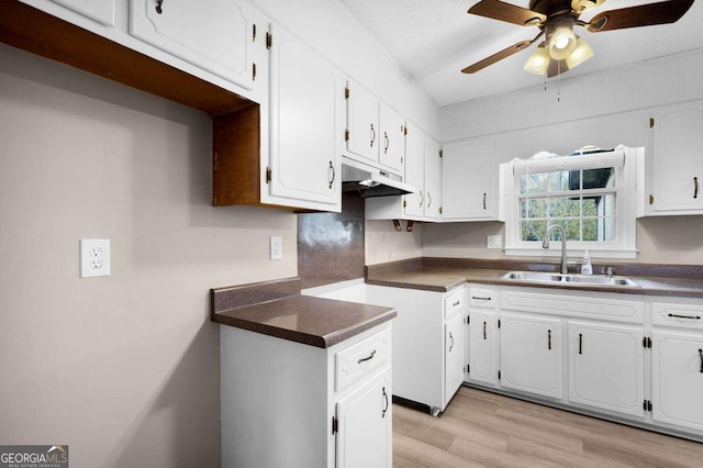 kitchen featuring white cabinets, a textured ceiling, light hardwood / wood-style floors, and sink