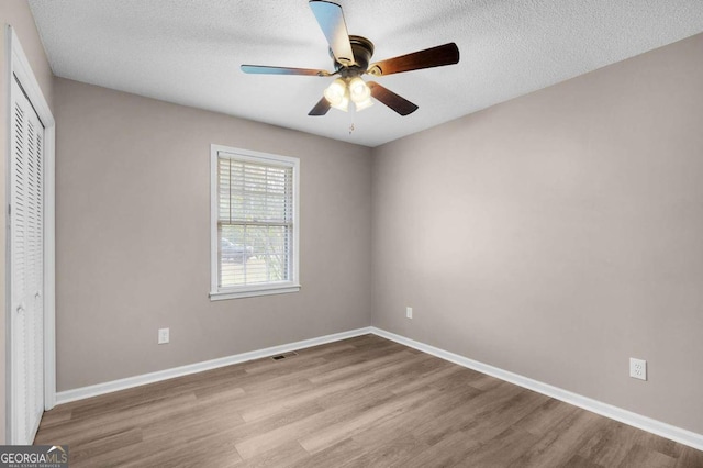 unfurnished bedroom with ceiling fan, a closet, light hardwood / wood-style floors, and a textured ceiling