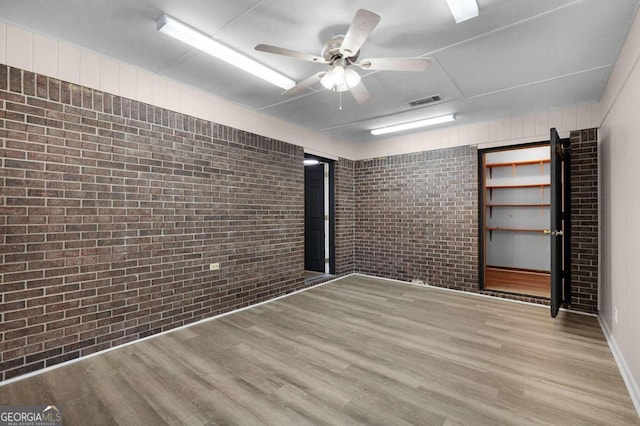 spare room with ceiling fan, brick wall, and light hardwood / wood-style flooring