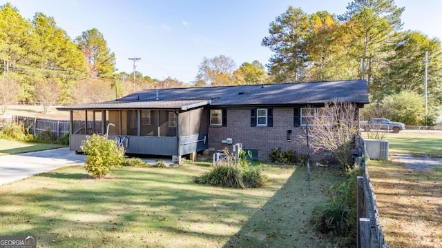 rear view of property with a sunroom, a yard, and central AC unit