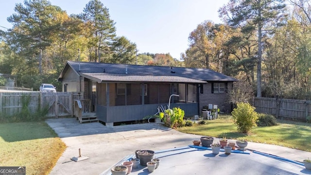 rear view of property featuring a lawn, a sunroom, and a patio