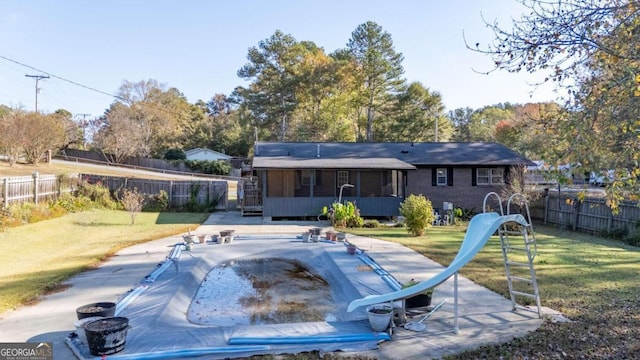 view of pool featuring a sunroom, a yard, and a water slide