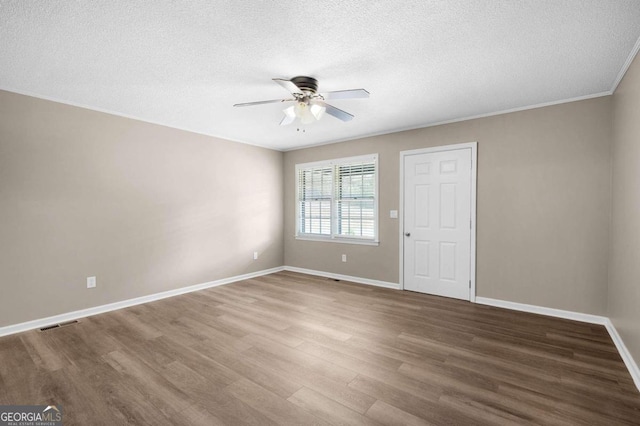 spare room featuring ceiling fan, wood-type flooring, a textured ceiling, and ornamental molding