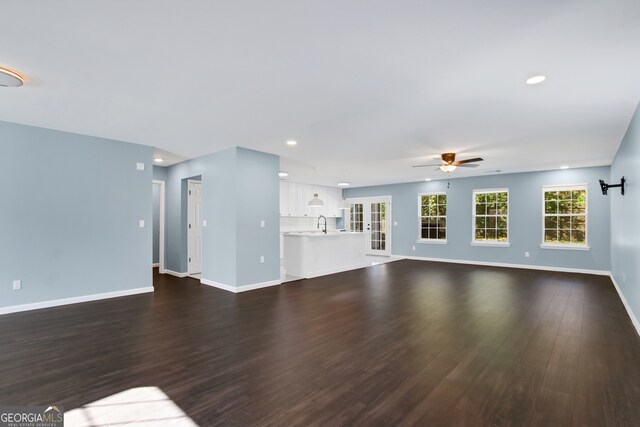 unfurnished living room with dark hardwood / wood-style floors and ceiling fan