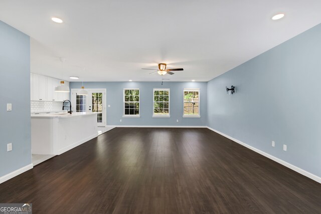 unfurnished living room featuring ceiling fan, french doors, dark wood-type flooring, and sink