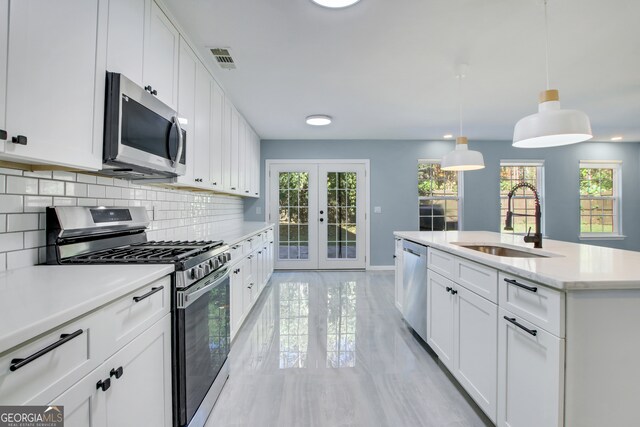 kitchen with white cabinetry, french doors, pendant lighting, and appliances with stainless steel finishes