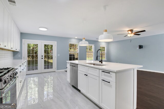 kitchen with decorative light fixtures, stainless steel appliances, white cabinetry, and a wealth of natural light