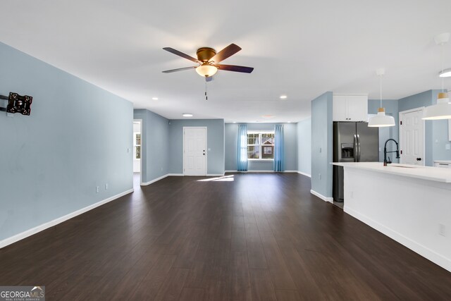 unfurnished living room with ceiling fan, sink, and dark wood-type flooring