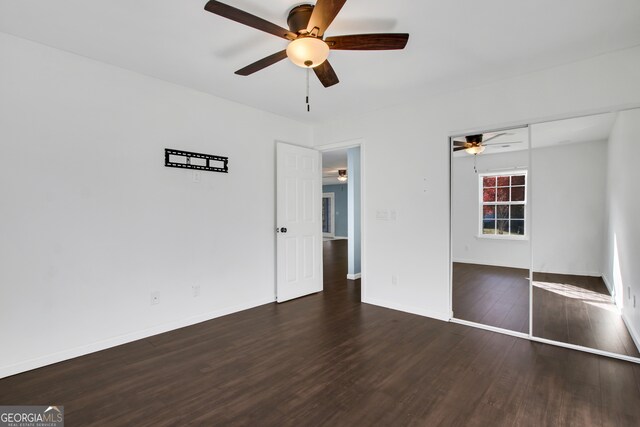 unfurnished bedroom featuring ceiling fan, a closet, and dark wood-type flooring