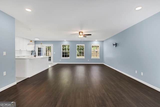 unfurnished living room featuring ceiling fan, dark hardwood / wood-style flooring, french doors, and sink