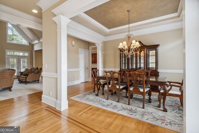 dining area with hardwood / wood-style flooring, a notable chandelier, ornate columns, and ornamental molding