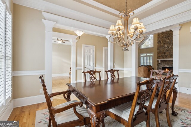 dining area with ceiling fan with notable chandelier, ornamental molding, a wealth of natural light, and light hardwood / wood-style flooring