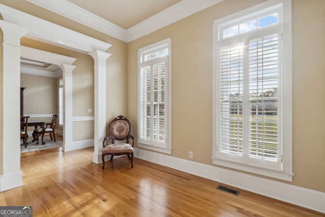 unfurnished room featuring hardwood / wood-style flooring, ornate columns, and ornamental molding