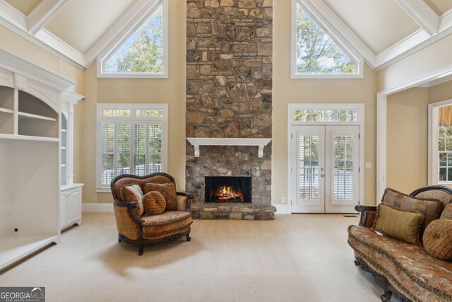 carpeted living room featuring beamed ceiling, french doors, high vaulted ceiling, and a stone fireplace