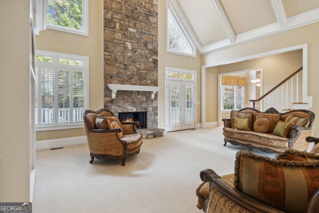 living room featuring an inviting chandelier, beamed ceiling, high vaulted ceiling, light colored carpet, and a fireplace