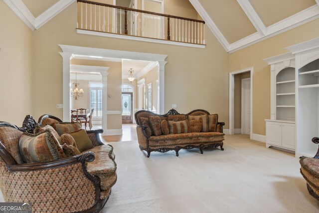 living room with high vaulted ceiling, crown molding, carpet flooring, a notable chandelier, and decorative columns