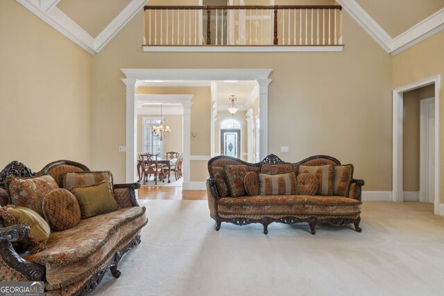 carpeted living room featuring high vaulted ceiling, ornate columns, and ornamental molding