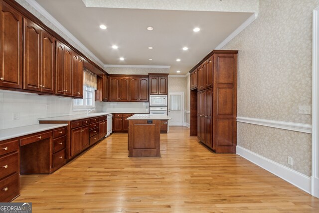 kitchen featuring sink, a center island, light hardwood / wood-style flooring, white appliances, and ornamental molding