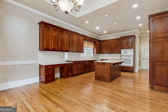 kitchen featuring a center island, white appliances, ornamental molding, a notable chandelier, and light hardwood / wood-style floors