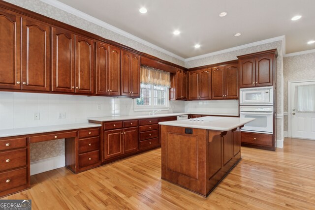 kitchen with built in desk, white appliances, ornamental molding, and light hardwood / wood-style flooring