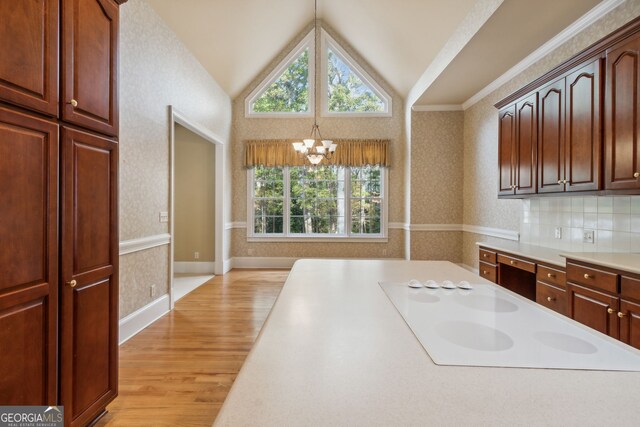 kitchen with lofted ceiling, hanging light fixtures, white electric cooktop, light wood-type flooring, and a chandelier