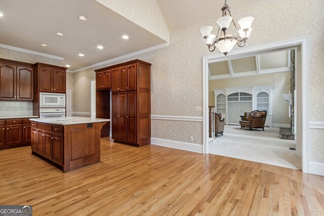 kitchen with crown molding, decorative light fixtures, white appliances, and light wood-type flooring