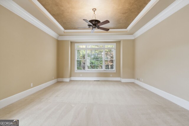 empty room with a tray ceiling, ceiling fan, and ornamental molding