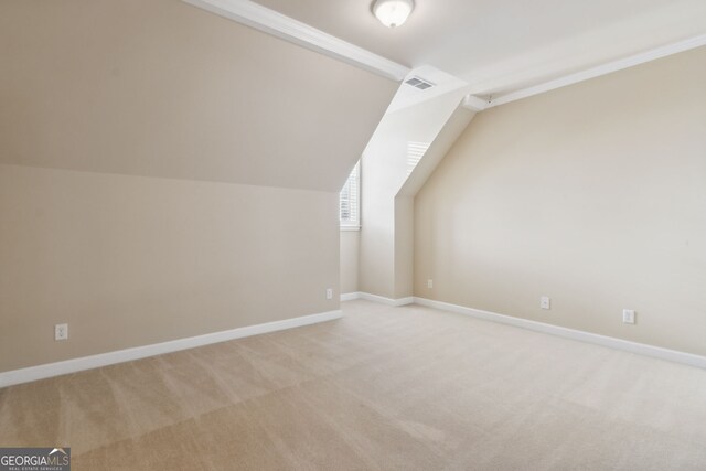 bonus room with light colored carpet and vaulted ceiling