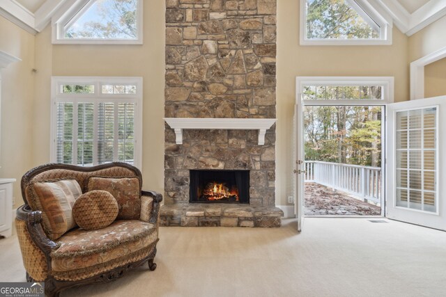 carpeted living room featuring high vaulted ceiling and a stone fireplace