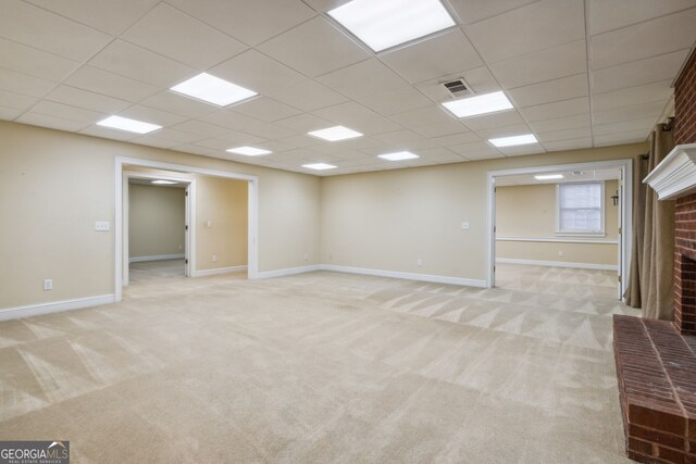 basement with a fireplace, light colored carpet, and a drop ceiling