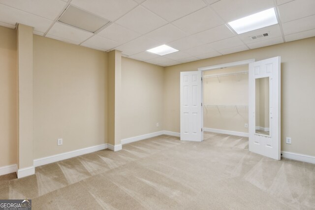 interior space with a drop ceiling and light colored carpet