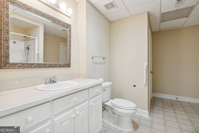 bathroom featuring walk in shower, vanity, toilet, and a drop ceiling