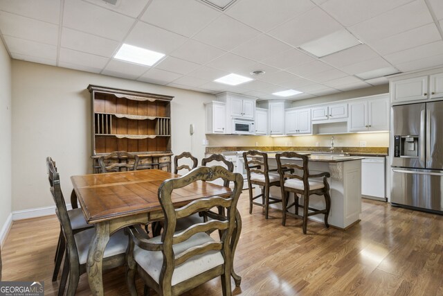 dining room featuring a paneled ceiling, light hardwood / wood-style flooring, and sink