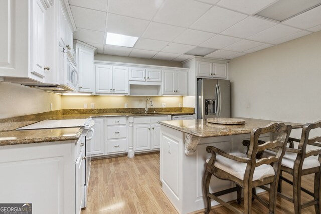 kitchen with white cabinetry, sink, light hardwood / wood-style floors, white appliances, and a kitchen island